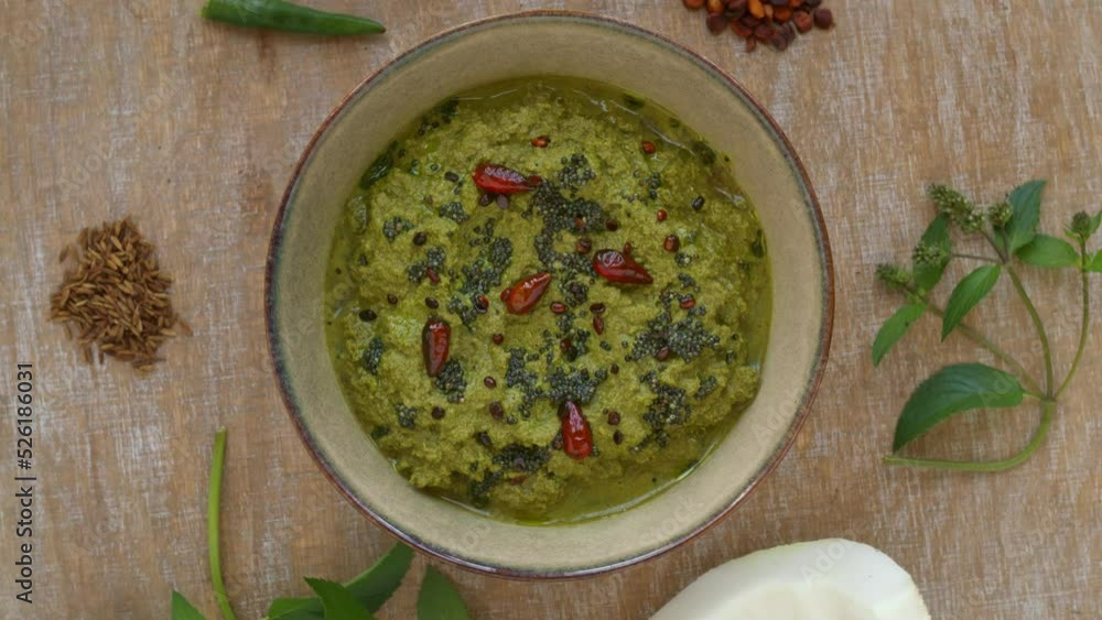 Mint and coconut chutney (Pudina chutney) in bowl with main ingredients: mint, coconut, roasted chana dal, cumin and green chilies. Top view, table spin. Mint and coconut chutney (Pudina chutney) in bowl with main ingredients: mint, coconut, roasted chana dal, cumin and green chilies. Top view, table spin.