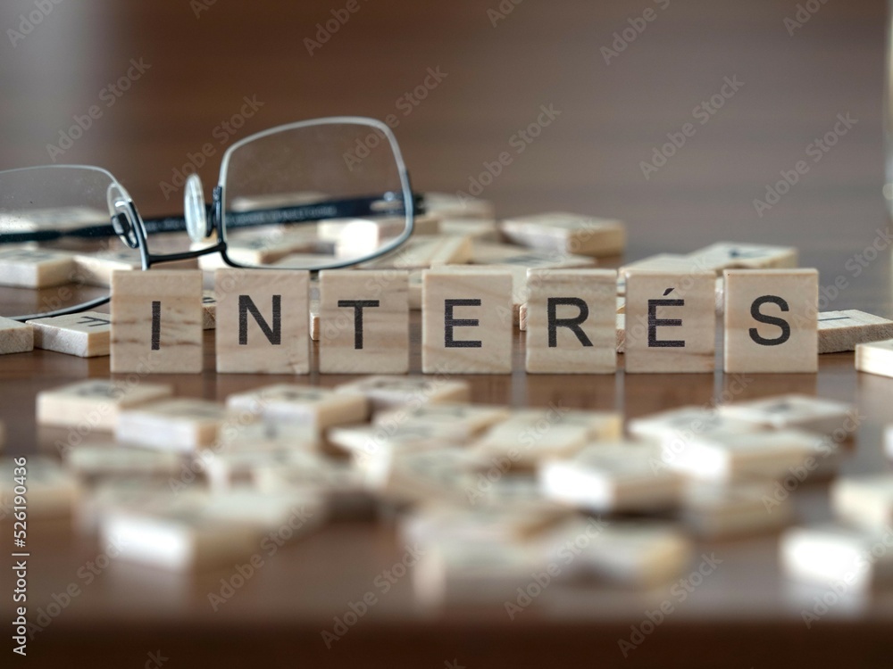 interés palabra o concepto representado por baldosas de letras de madera sobre una mesa de madera con gafas y un libro - obrazy, fototapety, plakaty 