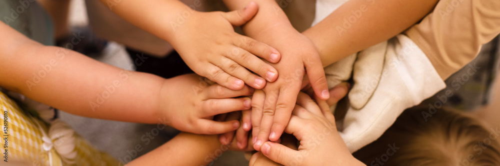 Children's hands piled on top of each other. Children's team and team building among the little child. Web banner Children's hands piled on top of each other. Children's team and team building among the little child. Web banner