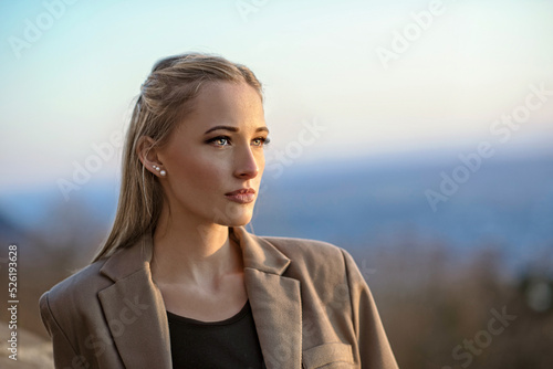 Eine junge, blonde Frau schaut nachdenklich ernst in die Weite. 