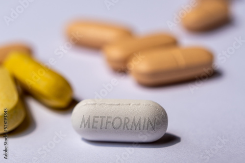 White Metformin Pill on Table with stethoscope and other tablets in background. Medicine used in standard oral therapy of type 2 diabetes in people who are overweight High Blood Sugar Treatment photo