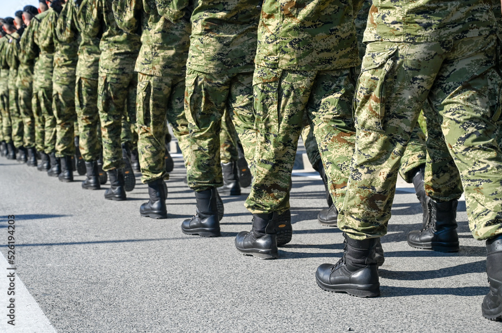 Soldiers in camouflage uniform and black boots marching in formation on parade. Special armed forces.  