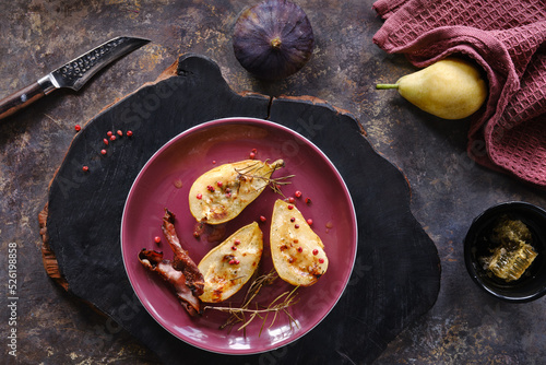 Baked pears with honey and red pepper. Flat lay, top view with fresh fig fruits and red towel on dark textured background.