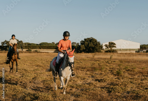 rider dressed in pink as her white horse rides in front of another rider