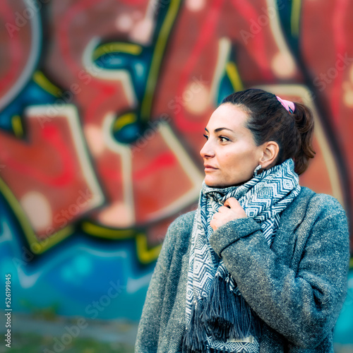 Portrait of an adult caucasian woman looking to a vanishing point outdoors with a painted wall as background