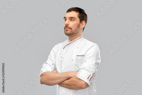cooking, culinary and people concept - male chef in jacket with crossed arms over grey background © Syda Productions