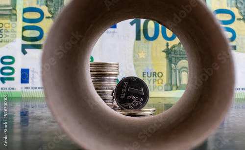 1 russian ruble coin close-up on background of euro banknotes inside blurred paper pipe background photo