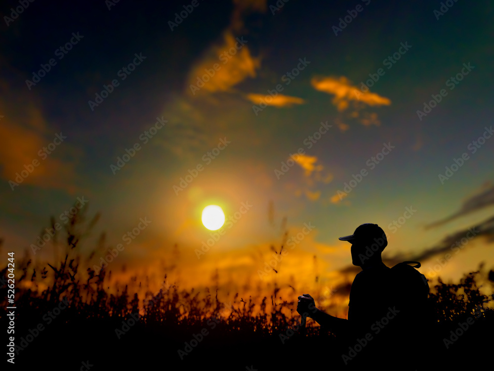 silhouette of a man, walking through the grass, in the evening, at sunset, backpacking adventure travel camping