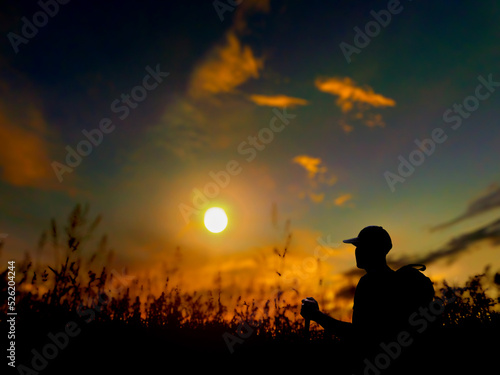 silhouette of a man, walking through the grass, in the evening, at sunset, backpacking adventure travel camping