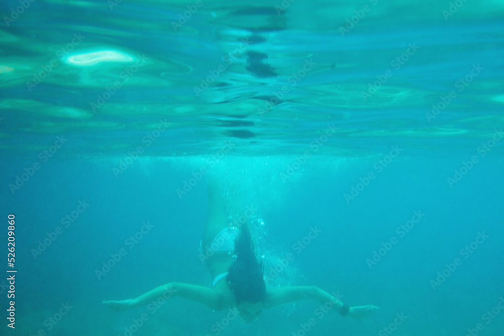 Obraz premium Beautiful woman swimming underwater on paradise beach freedom wellbeing lifestyle summer vacation wanderlust