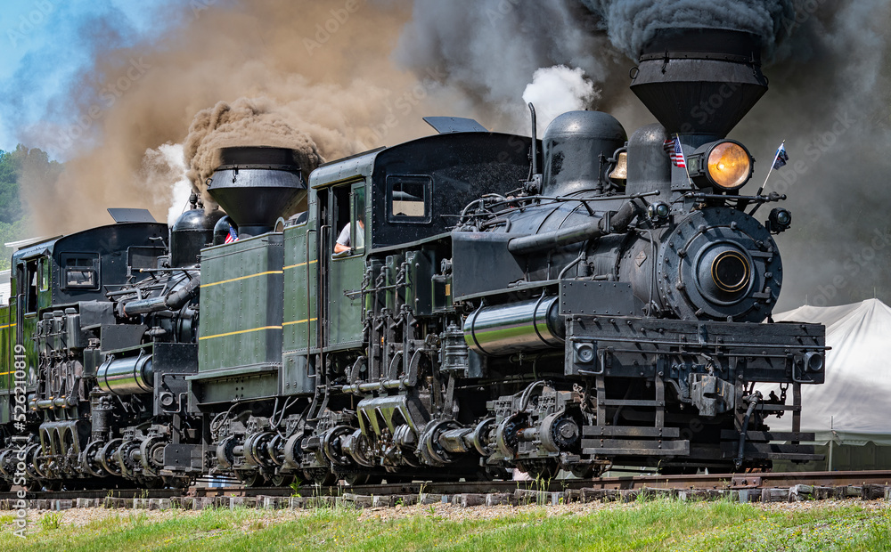 View of Two Shay Steam Engines, Heading Out for a Parade of Steam With the Two Engines Connected Together Blowing Black Smoke and White Steam on a Sunny Summer Day View of Two Shay Steam Engines, Heading Out for a Parade of Steam With the Two Engines Connected Together Blowing Black Smoke and White Steam on a Sunny Summer Day
