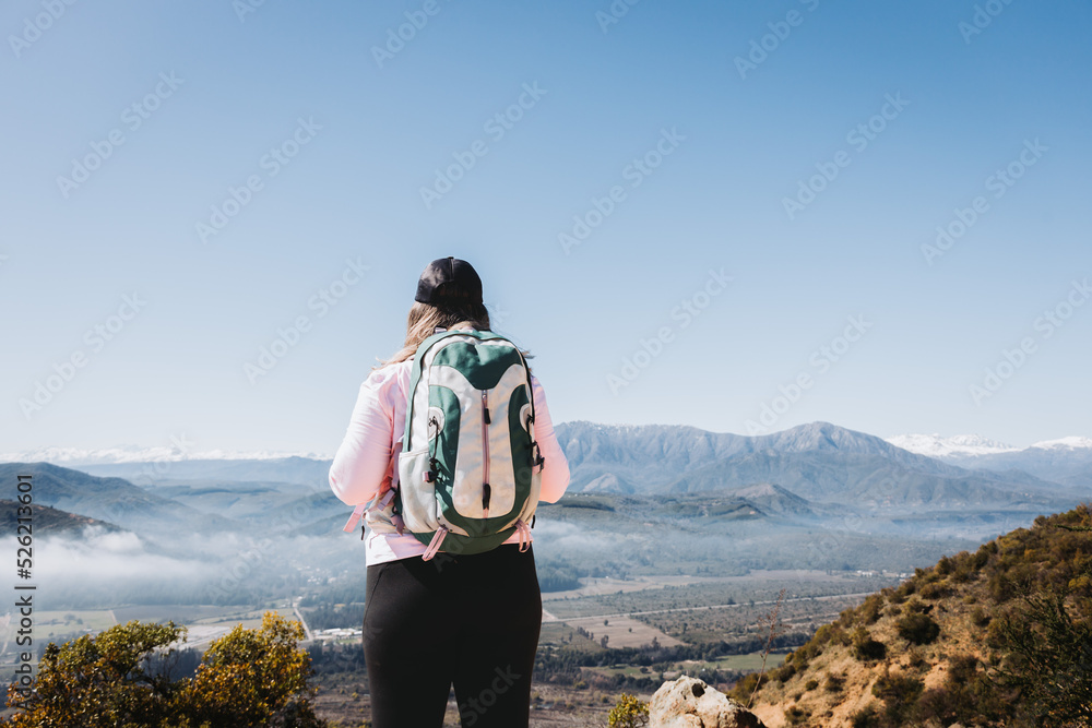 Rear view young latin plus size woman with backpack on, at the top of a hill 