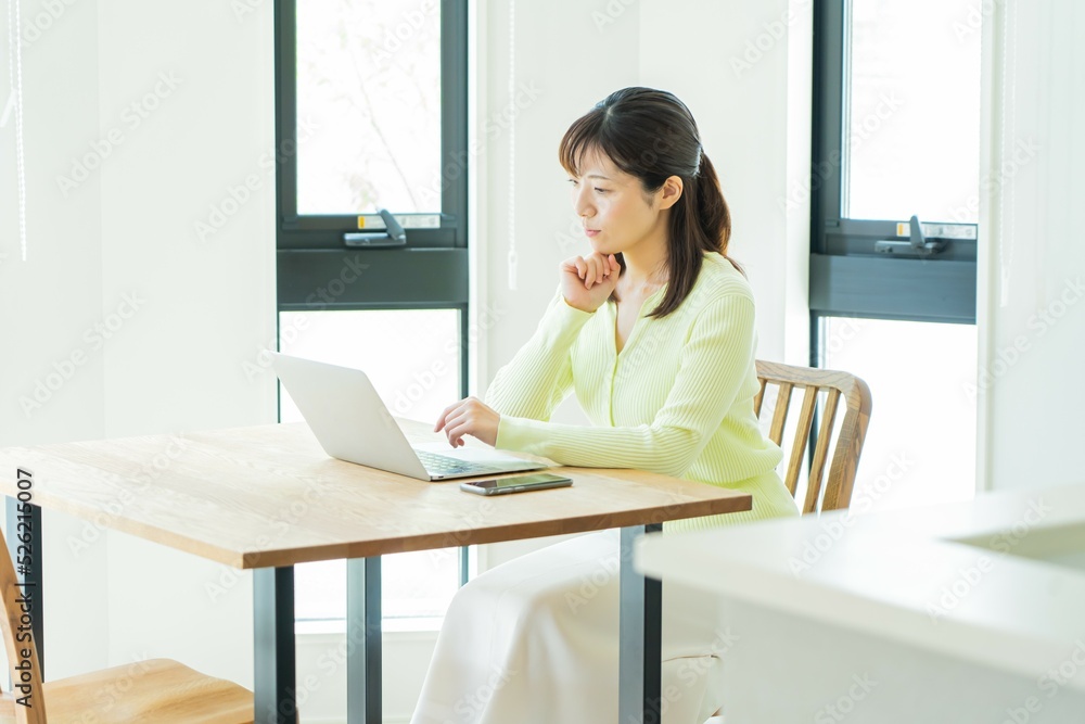 自宅のソファでくつろぎながら携帯を触る日本人女性 自宅のソファでくつろぎながら携帯を触る日本人女性