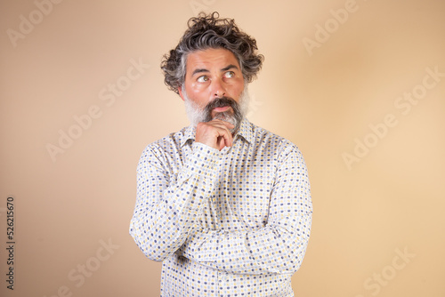 Canvas Print Middle age grey-haired man in casual clothes with hand on chin thinking about question, expression of penitence