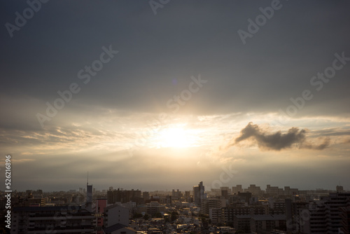 都市の夜明け。日の出とともに空と雲がオレンジ色に染まり、ビル群はシルエットとして写す