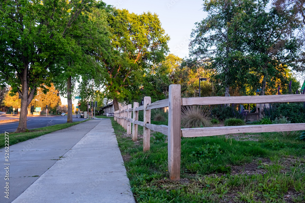 A sidewalk and a wooden fence A sidewalk and a wooden fence