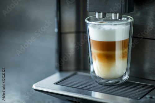 Espresso machine making fresh coffee latte. Shot of espresso being pour into fresh steamed milk