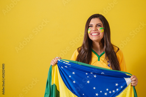 Woman supporter of Brazil, 2022 world cup, soccer championship, holding flag waving victory.