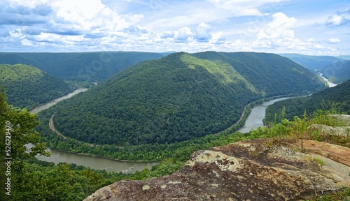 looking out at a horseshoe bend in the new river, railway,   and forested  hills in summer from the grandview main overlook in the new river gorge national park, west virginia photo