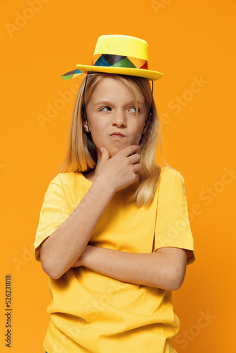 funny miya girl stands in a very thoughtful pose on a yellow background in a wicker hat