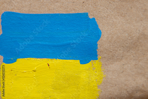 The flag of Ukraine is painted with paints on brown paper