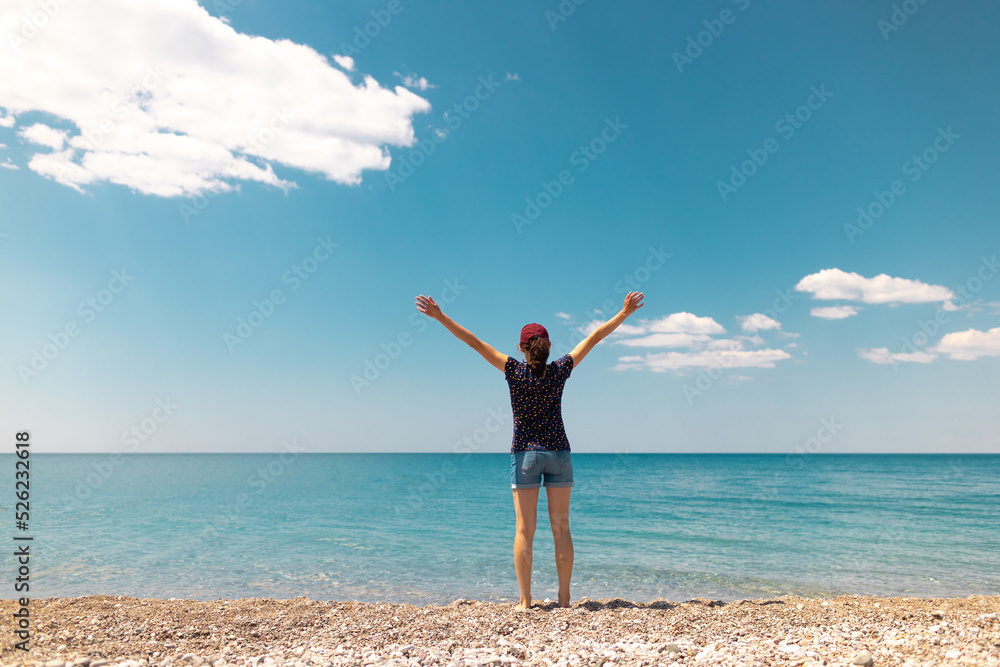 The girl is walking on the seashore and looking at the water