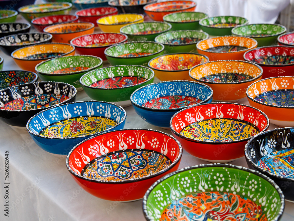 Fototapeta premium Authentic hand made Turkish ceramic bowls with vibrant bright colours and intricate hand painted design at local market. Sourced from Turkey. Can be used as home decor or for serving. Iznik pottery.