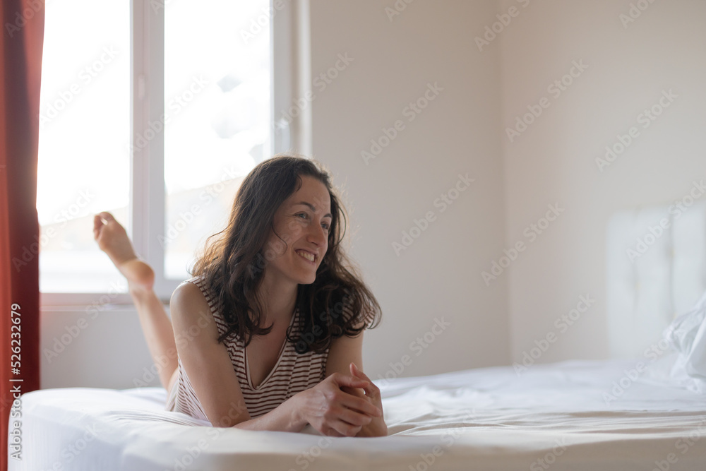 Happy young girl with dark curly hair sitting in bed in the morning Happy young girl with dark curly hair sitting in bed in the morning