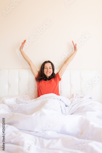 The girl sits on the bed and stretches, the woman woke up