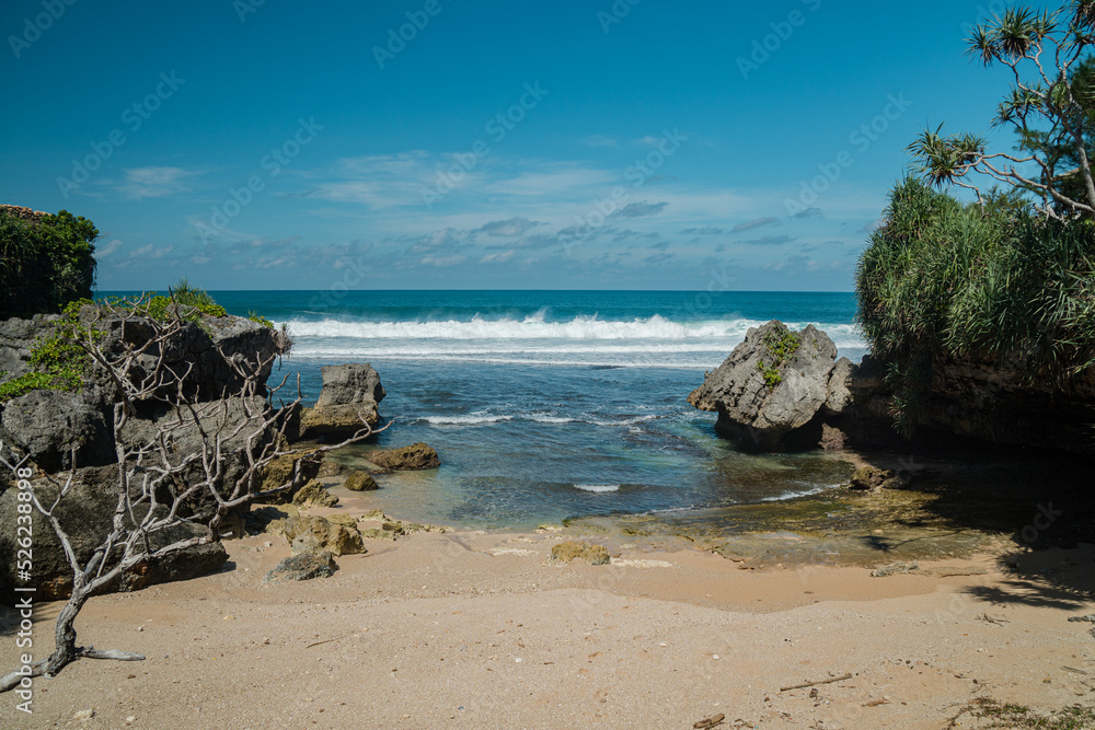 A beautiful and natural white sand beach with rolling waves on the southern coast of Yogyakarta, Indonesia. This exotic beach has great waves and stunning natural scenery