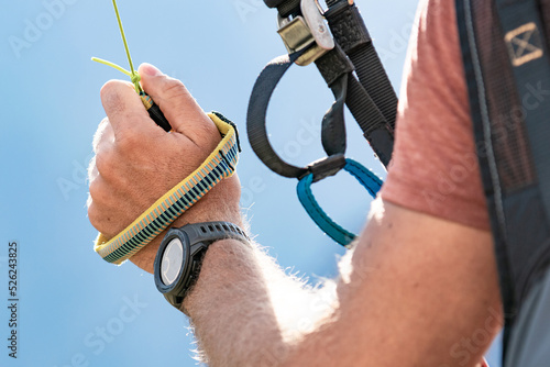 A hand of a pilot with a toggle of a paraglider