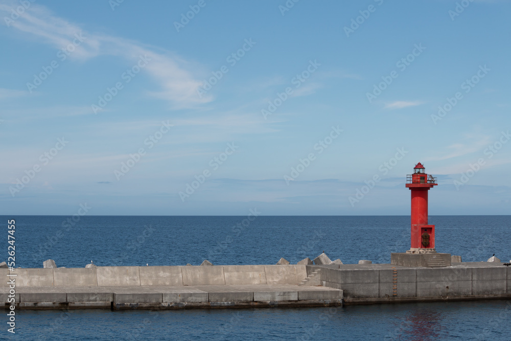A red lighthouse on a harbour wall