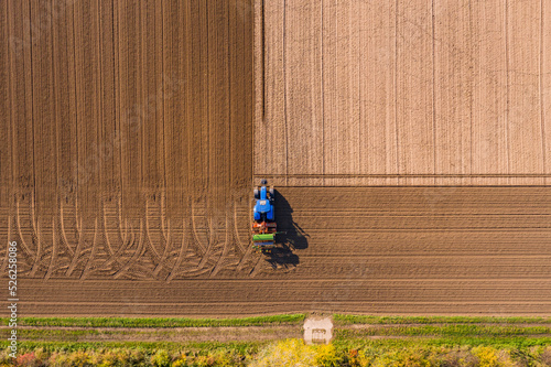 Foto Aerial view of blue tractor plowing a field leaving tire tracks