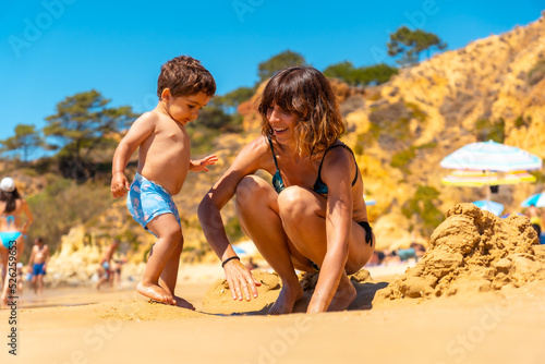 Mother and son playing on the beach at Praia do Barranco das Belharucas, Albufeira, Algarve. Portugal