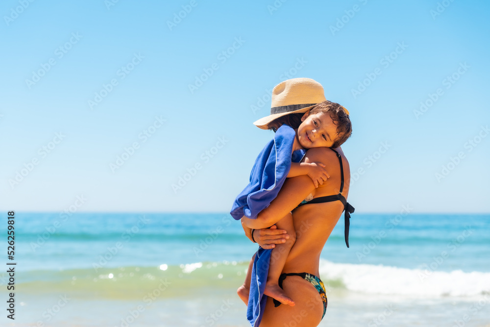 Mother with hat hugging and having fun with her son by the sea, Algarve beach, Albufeira. Portugal Mother with hat hugging and having fun with her son by the sea, Algarve beach, Albufeira. Portugal
