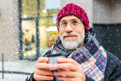 goog looking mature man drink hot tea in city street at winter