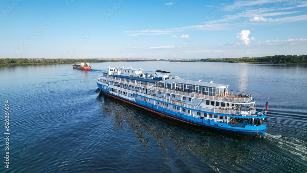 Cruises on the liner along the Volga. Passenger ship with tourists on board flying to overtake a tanker in Volgograd.