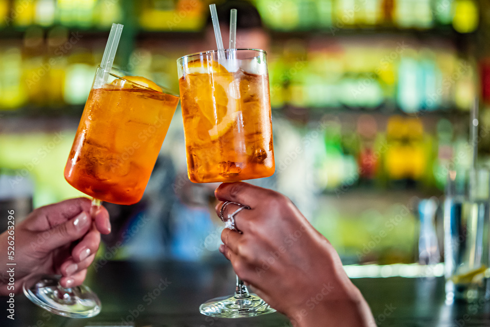 girls hand at the bar clink glasses with cocktails