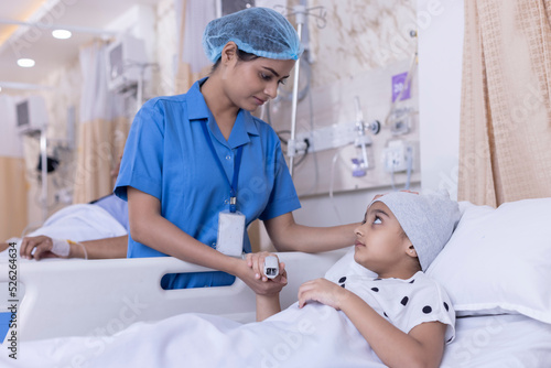 Fotografia Young nurse visiting and consoling little girl lying on bed