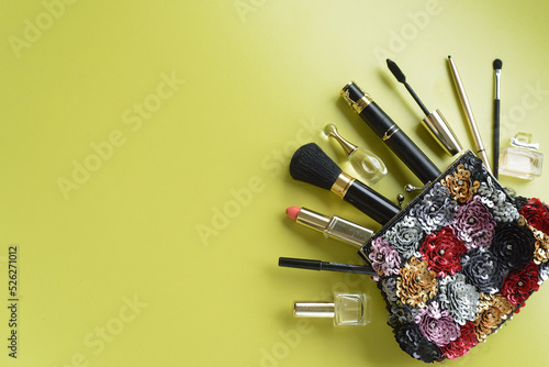 make up bag with cosmetics and brushes on green background. top view. copy space.