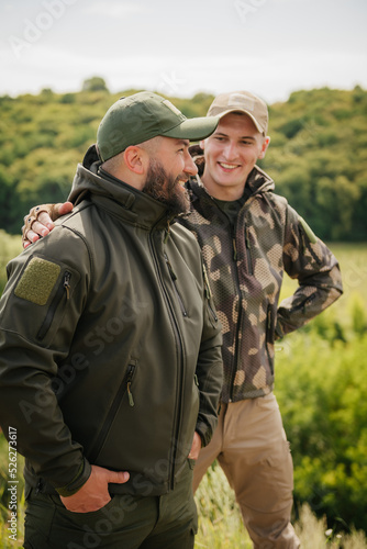 Fototapet Two guys hunters fishers wearing tactical hunter gear happy meet each other and