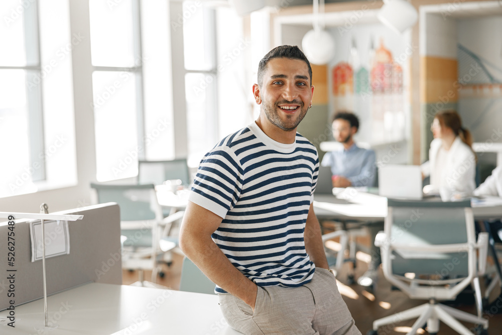 Fototapeta premium Portrait of smiling businessman in casual clothes standing in modern office 