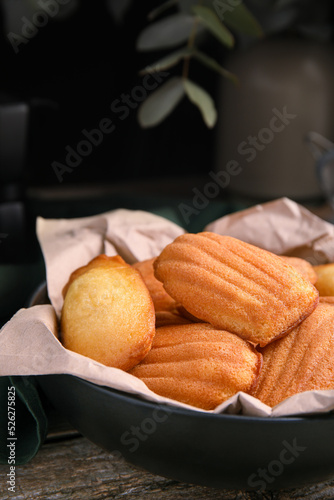 Delicious madeleine cakes in bowl on wooden table, closeup