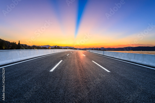 Empty asphalt road and beautiful mountain with colorful sky clouds at sunrise