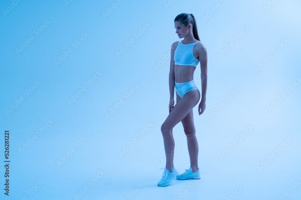 Full length shot of female fitness model in sportswear outfit after workout under neon light