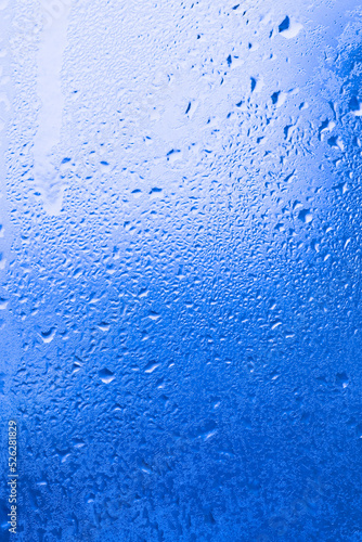 Texture of ice on the glass, icy surface of a frozen window, background, blue monochrome.