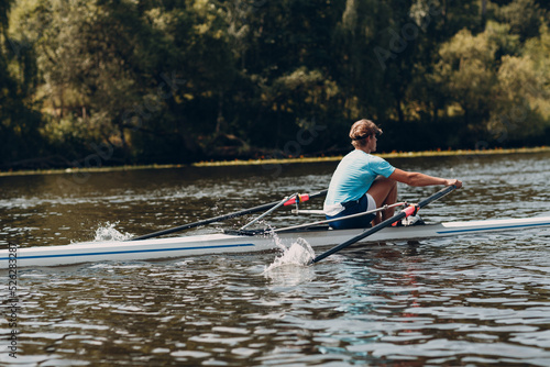 Sportsman single scull man rower rowing on boat. Paddle splash movement