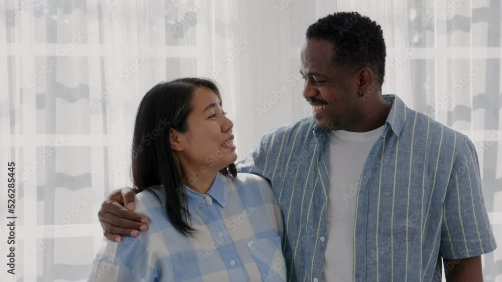 An interracial couple makes romantic eye contact and smiles on Valentine's Day. An interracial couple makes romantic eye contact and smiles on Valentine's Day.