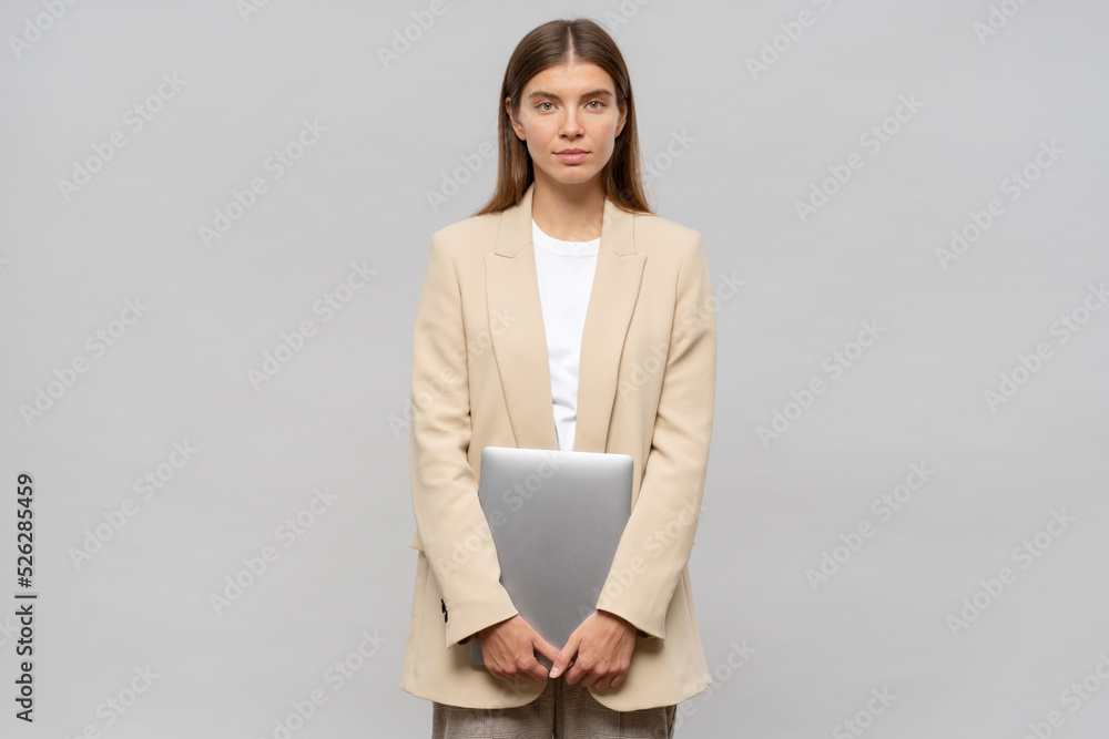 Portrait of shy student girl feeling nervous standing isolated on gray background with laptop - obrazy, fototapety, plakaty 