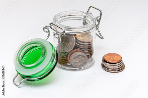 Metal coins in stacks, a calculator for counting money, a jar with small coins on a white background, close-up, selective focus.Concept: financial savings, expenses and income.